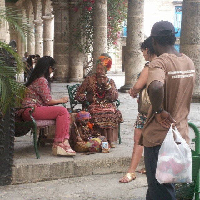 People talking on rocking chairs on cuban street